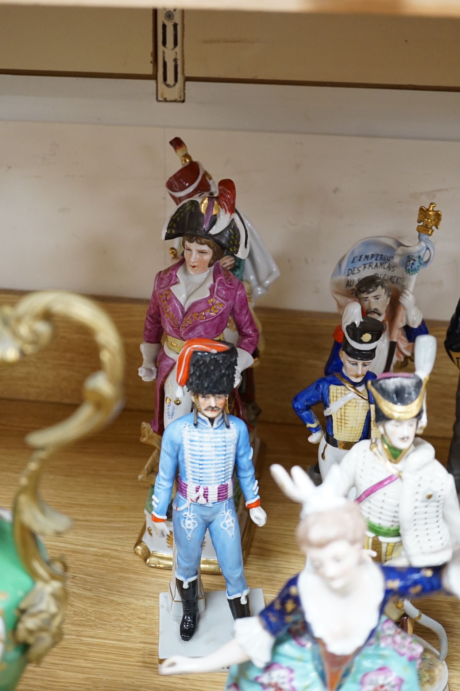 A group of Continental porcelain military figures, two porcelain figures of dancing females and four pieces of tableware in the form of fruit